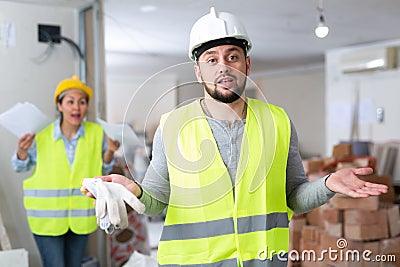 Puzzled worker standing at construction site with screaming female foreman Stock Photo