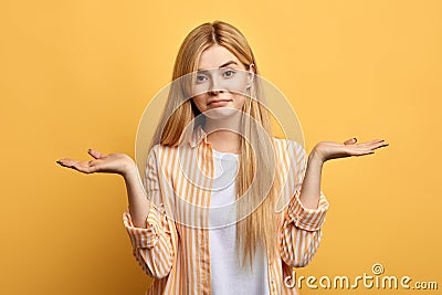 Puzzled hesitant girl with long fair hair with raised arms looking at the camera Stock Photo