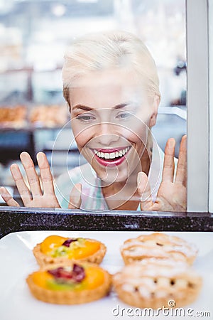 Puzzled pretty woman looking at a fruit pie through the glass Stock Photo