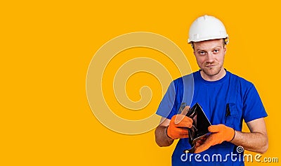 The puzzled worker in overalls holds his empty purse without money. The concept of economic crisis, unemployment and production, Stock Photo