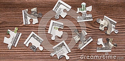 Puzzles of banknotes hundred-dollar money are disassembled against the background of a natural wood texture. Stock Photo