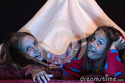 Pyjamas party for children. Girl friends under blanket Stock Photo