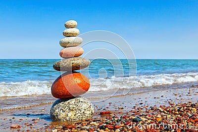 Pyramid of colored pebbles on a background of the summer sea. Concept of harmony, balance and meditation Stock Photo