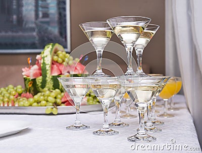 Pyramid of glasses of sparkling wine, fruit in the background Stock Photo