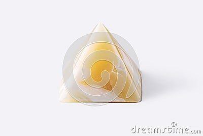 Pyramid made from yellow onyx possesses mystical properties. Souvenir semiprecious stone on a white background Stock Photo