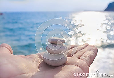 Pyramid of stones on hand palm sea glare water background Stock Photo