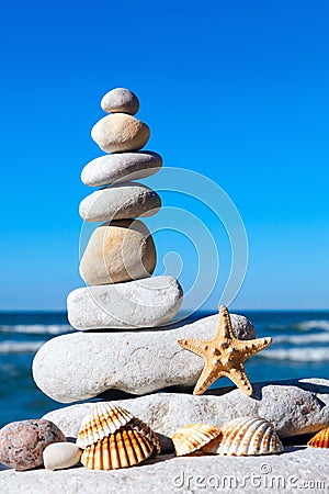 Pyramid of white stones and shells on a background of blue sky and sea Stock Photo