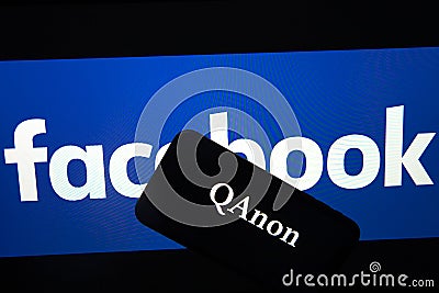 QAnon vs FACEBOOK. QAnon organization logo seen on the smartphone which is placed on Facebook logos. Editorial Stock Photo