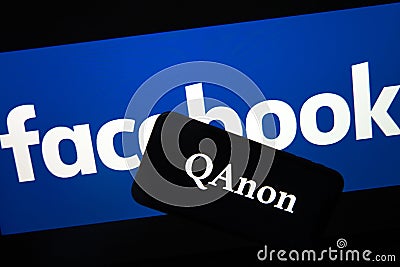 QAnon vs FACEBOOK. QAnon organization logo seen on the smartphone which is placed on Facebook logos. Editorial Stock Photo