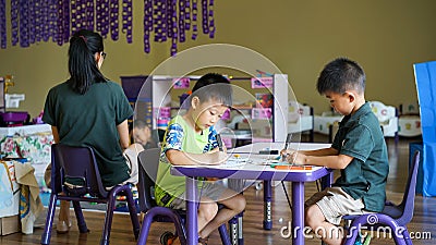 Qingyuan, China - June 23, 2016: Two little boys in the classroom sitting under the table during the class Editorial Stock Photo