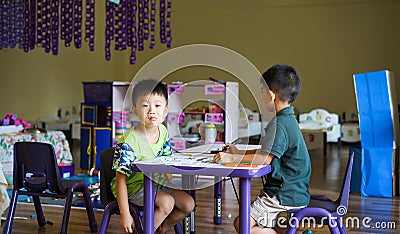 Qingyuan, China - June 23, 2016: Two little boys in the classroom sitting under the table during the class Editorial Stock Photo