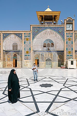 Qom, Iran - 04.20.2019: Islamic woman in tradiitonal black dress walking under in the courtyard of Fatima Masumeh Shrine. Hazrat Editorial Stock Photo