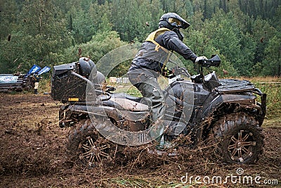 Quad rider jumping on a muddy forest trail Editorial Stock Photo
