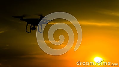 Quadrocopters silhouette against the background of the sunset. Flying drones in the Stock Photo
