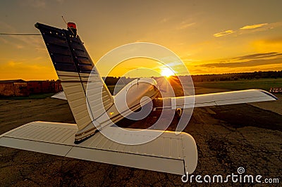 Quadruple aircraft parked at a private airfield. Rear view of a plane with a propeller on a sunset background. Stock Photo