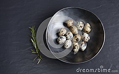 Quail eggs in ceramic black bowl on black ceramic background and Stock Photo