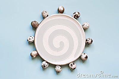 Quail eggs and white rustic plate on pastel blue background. Minimal Easter composition Stock Photo