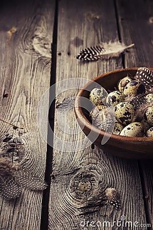 Quail eggs in a wooden bowl on a gray wooden background. Stock Photo