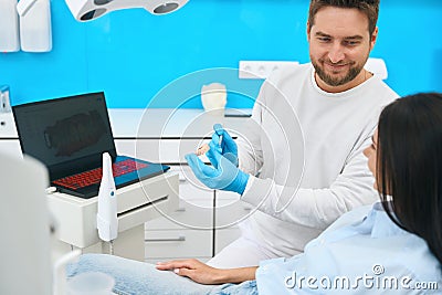 Qualified dental technician showing to client how to clean dental prosthesis Stock Photo