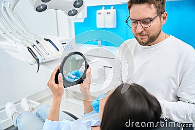Qualified dentist choosing color and size of veneers for female client Stock Photo