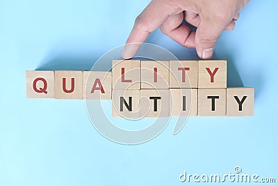 Quality over quantity concept. Hand changing word quantity to quality on wooden blocks. Stock Photo