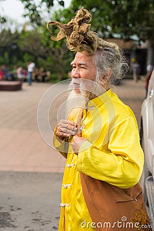 Quang Ninh, Vietnam - Mar 22, 2015: Portrait of old Vietnamese man with very long hair. He`s wearing Buddhist clothes Editorial Stock Photo