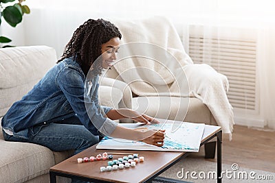 Quarantine Hobby. Relaxed Black Woman Drawing Painting By Numbers At Home Stock Photo