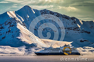 Quark Expeditions tour liner in front of a snowy jagged mountain near Svalbard, Norway Editorial Stock Photo