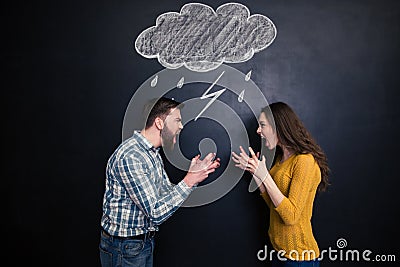 Quarrelling couple standing against background of chalkboard and screaming Stock Photo