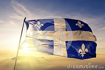 Quebec province of Canada flag textile cloth fabric waving on the top sunrise mist fog Stock Photo