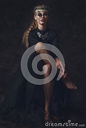 Queen of darkness in black fantasy costume on dark gothic background. High fashion beauty model with dark makeup. Stock Photo