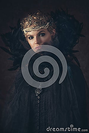 Queen of darkness in black fantasy costume on dark gothic background. High fashion beauty model with dark makeup. Stock Photo