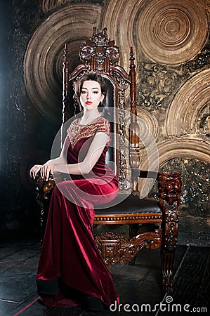 Queen in red dress sitting on throne. Symbol of power Stock Photo