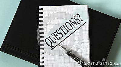 QUESTIONS? - word in a white notebook against the background of a black notebook with a pen Stock Photo