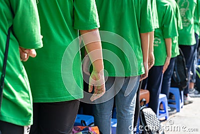 Queue of Asian teenagers in green t-shirt uniform standing in line Stock Photo