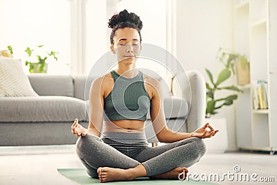 A quiet mind is the healthiest mind. Shot of a young woman meditating in her living room. Stock Photo