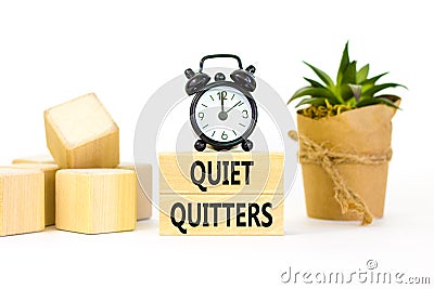 Quiet quitters symbol. Concept words Quiet quitters on wooden blocks. Beautiful white table white background. Black alarm clock. Stock Photo