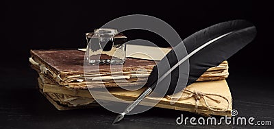 Quill, inkwell and old books on black table. Banner design Stock Photo