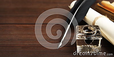 Quill, inkwell and paper roll on wooden table, space for text. Banner design Stock Photo