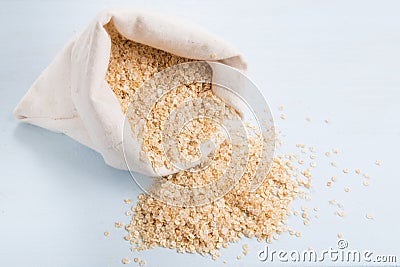 Quinoa flakes in a bag rolled top on a blue wooden board Stock Photo