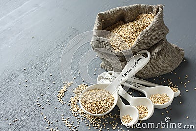 Quinoa grain in small burlap sack and porcelain measuring spoons Stock Photo