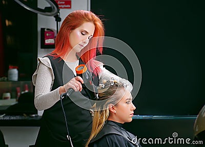 QUITO, ECUADOR - OCTOBER, 25, 2017: Close up of a hair stylist drying blond woman using a hair dryer and round brush in Editorial Stock Photo