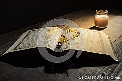 The Qur`an, the holy book of Islam. worship month of Ramadan, reading the scriptures by using a candle light. Stock Photo