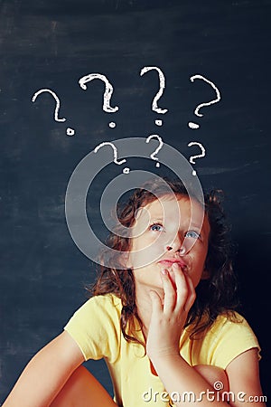 Qute kid next to chalkbord thinking' with many question marks symbols Stock Photo