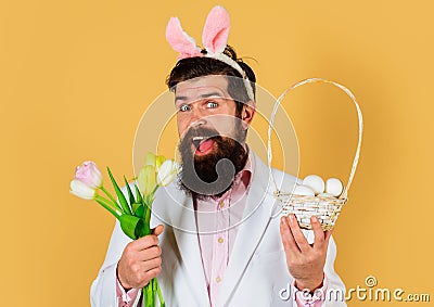 Rabbit man in bunny ears with flowers and basket eggs. Easter celebration concept. Bearded man in suit with Spring Stock Photo