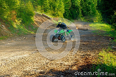 Racer with yellow helmet on green quad enjoying his ride outdoors. Stock Photo