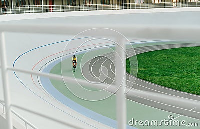 Racing cyclist on velodrome outdoor. Professional athlete in a yellow T-shirt does training on the velodrome. Background. Copy Editorial Stock Photo