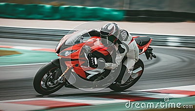 Racing motorbike rider in helmet and gear racing at high speed on race track with motion blur Stock Photo