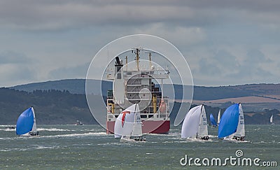Racing yachts and a containers ship on the Solent during Cowes Week regatta. Editorial Stock Photo