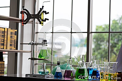 The rack held an array of colorful chemical glassware each piece shining with its own distinct hue creating a mesmerizing. Stock Photo